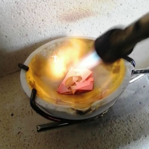 Scrap sterling silver being melted within crucible with a blow torch